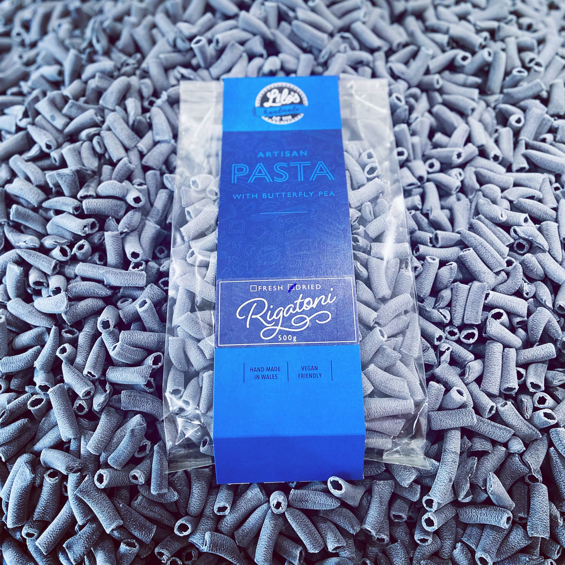 Pasta packaging with blue label on a bed of gray pasta