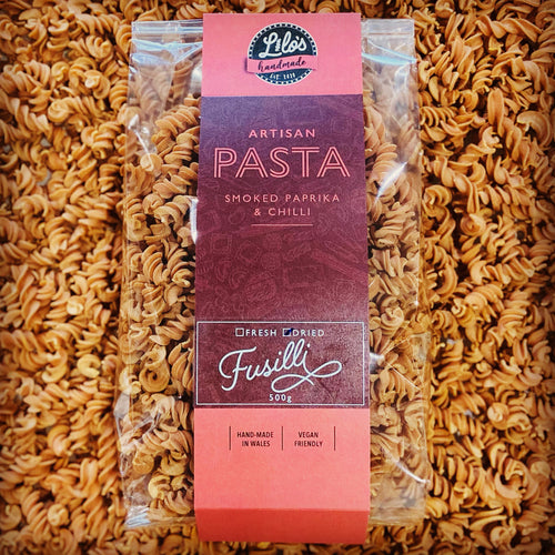 Packaged fusilli pasta with an orange label on a bed of fusilli pasta.
