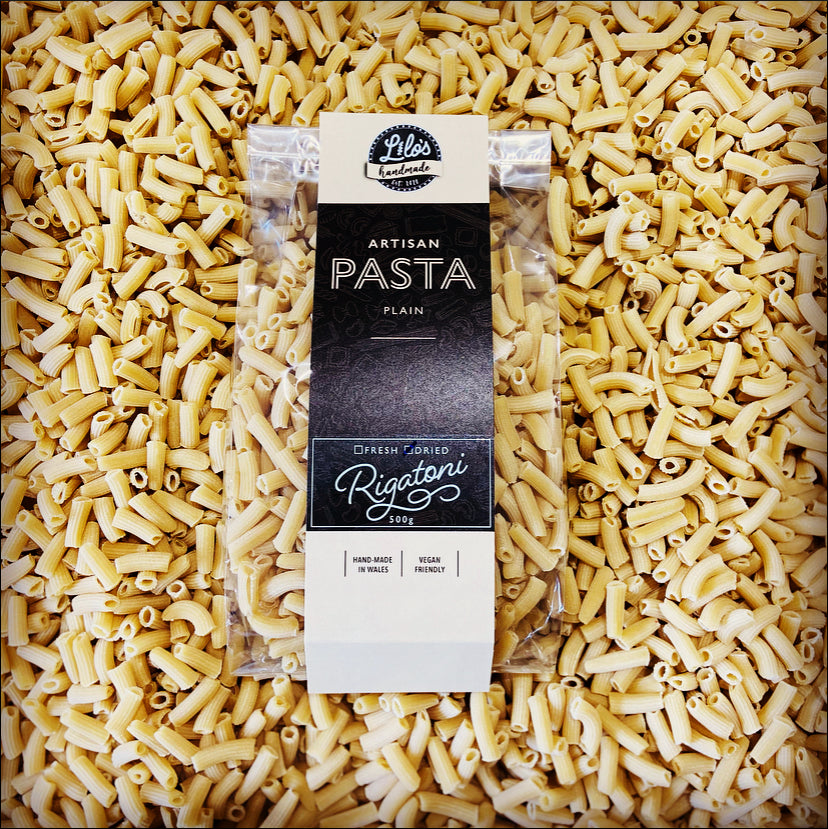 Packaged pasta with a brand label on a bed of uncooked pasta.