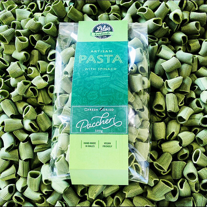 Packaged green pasta with a brand label on a bed of green pasta.