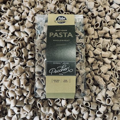 Packaged wholemeal pasta with a label on a bed of similar pasta.